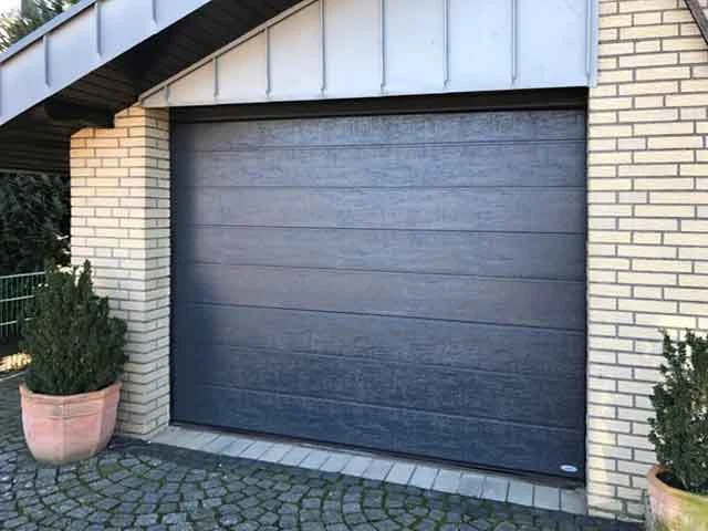 Passgenau montiertes anthrazitfarbenes Sektionaltor in einer Klinkerfassade